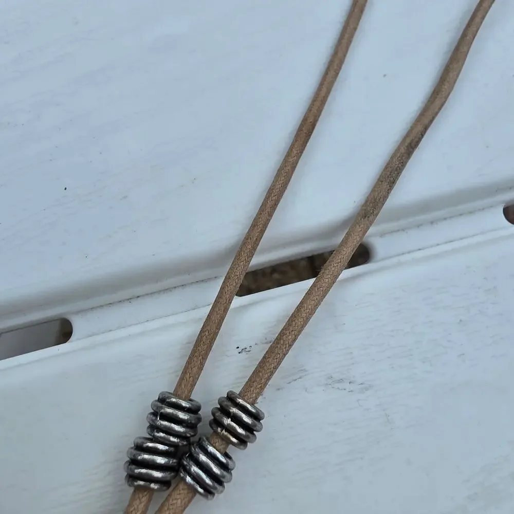 beige leather cord necklace with a silver-tone ring pendant